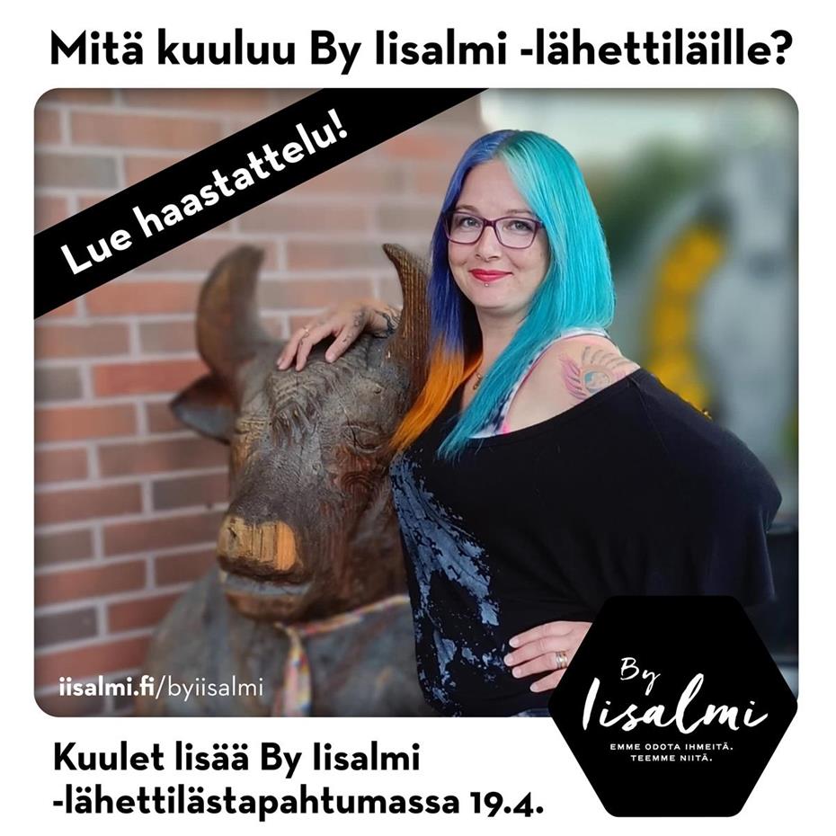 Arja Wäisänen poseeraa kuvassa hymyillen vieressään puusta veistetty härkäpatsas.